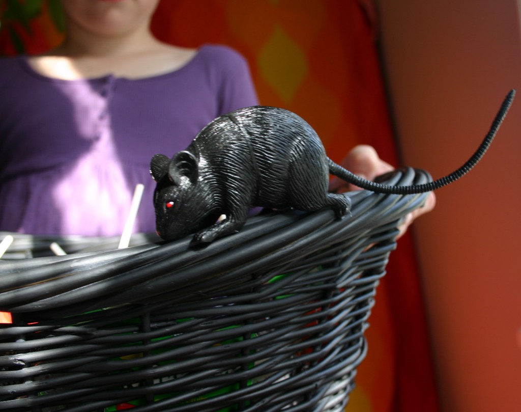 A rubber rat purchased at a Halloween supply store is hot-glued onto the edge of the basket.