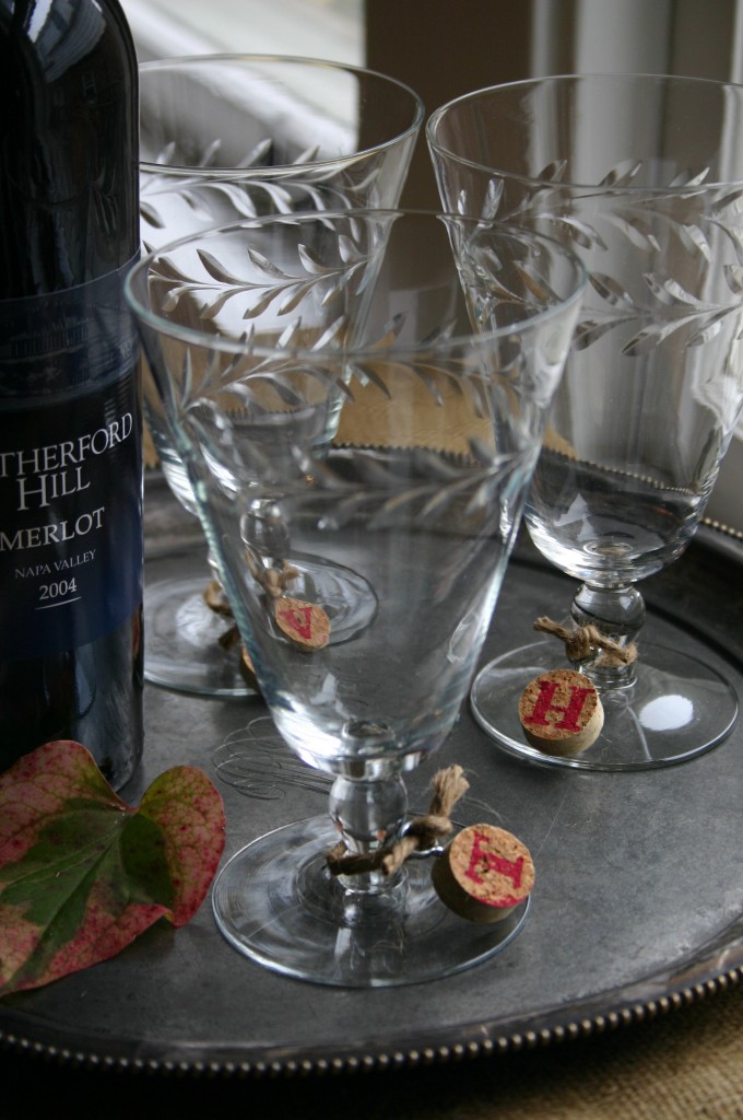 Wine corks, cut into half inch thick discs and rubberstamped with a letter are attached to the stem of a wine glass with jute.