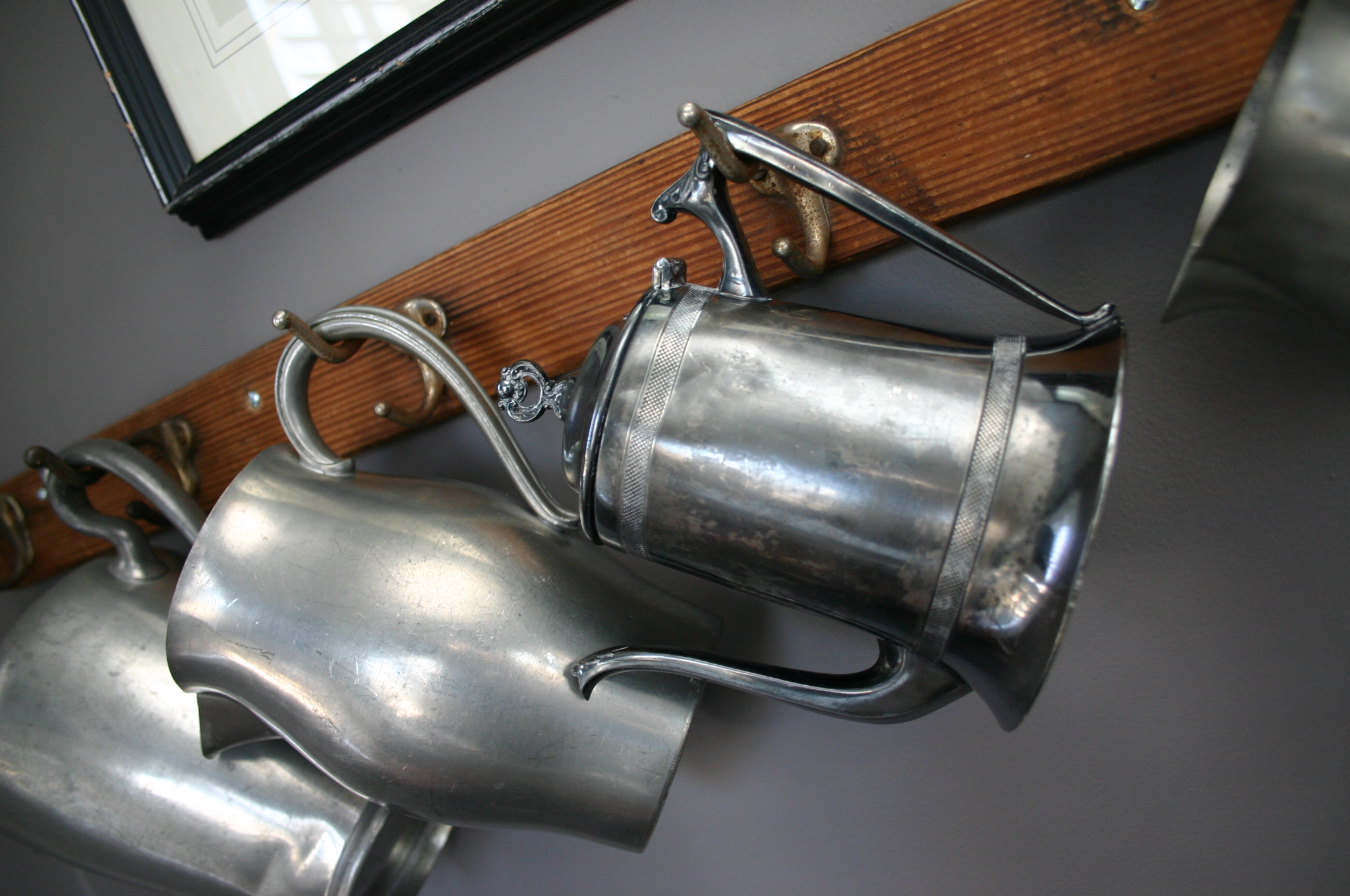 IMG_7709 I love pewter and silverplated pitchers. I cannot pass one up at a resale shop. Instead of displaying them all on one flat surface, I chose to hang them from hooks in our music room.