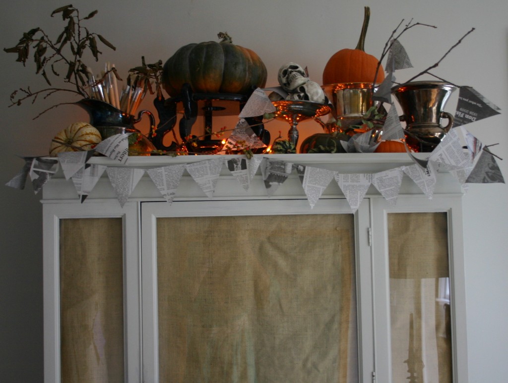 The top of our china closet - decorated with pumpkins, gourds, newspaper garland and silver.