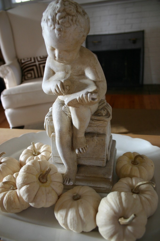 Miniature white pumpkins gathered around the base of a statue create a simple fall centerpiece for our coffeetable. 